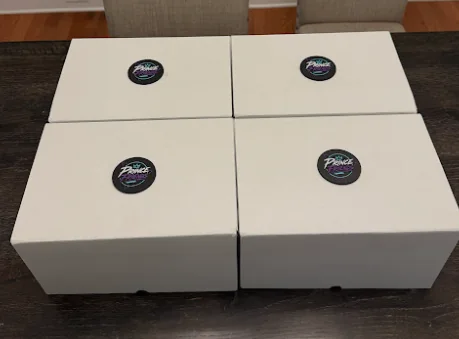 Four white gift boxes, each with a Prince Friends coin on the lid
