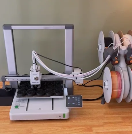 Our Bambu Lab A1 printer with a four-spool AMS Lite printing a plate of clicker bodies